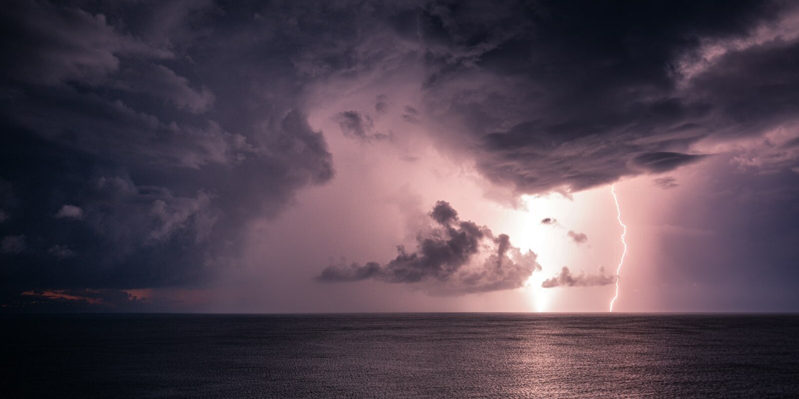 Thunderclouds with lightning over the sea Thunderclouds with lightning over the sea
