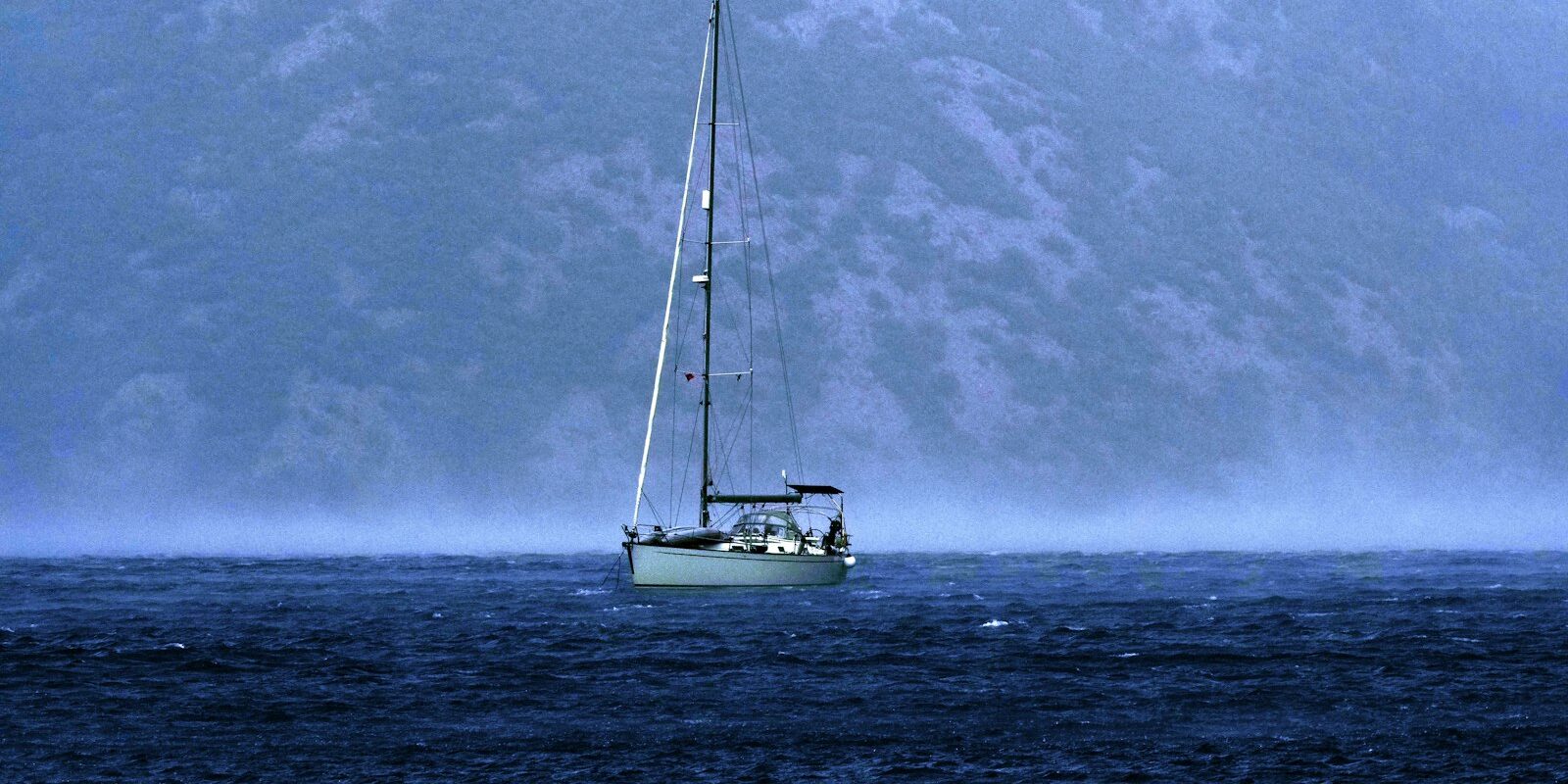 Sailing yacht on dark water beneath gathering clouds Sailing yacht on dark water beneath gathering clouds