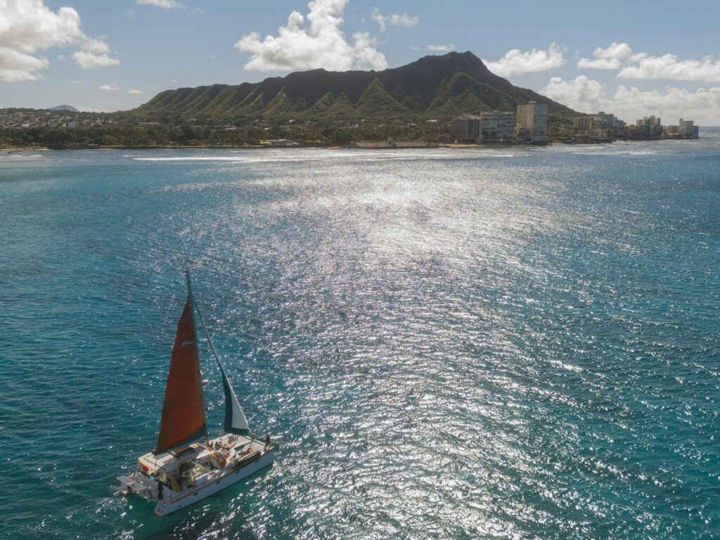 Segelboot unter Segeln vor einer Vulkaninsel